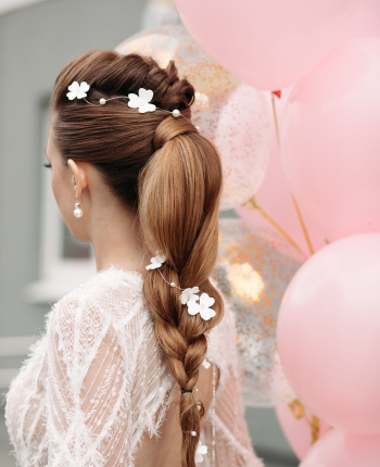 Slim stunning brunette with flowers in her hair and white dress.
