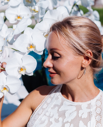 outdoor-portrait-woman-white-wedding-dress-sitting-near-blue-swimming-pool-with-flowers
